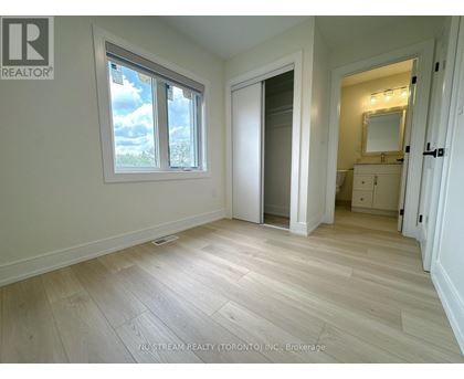 A room with a large window and a door leading to another room.