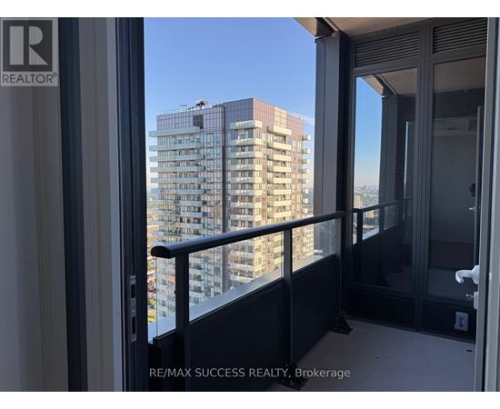 A balcony with a glass door overlooking a high-rise building.