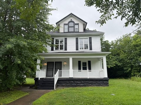 A white house with a black roof and a porch.