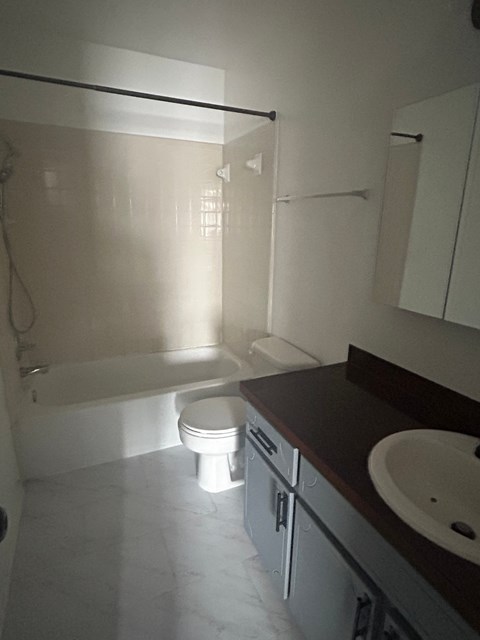 A white toilet sits in a bathroom next to a sink.