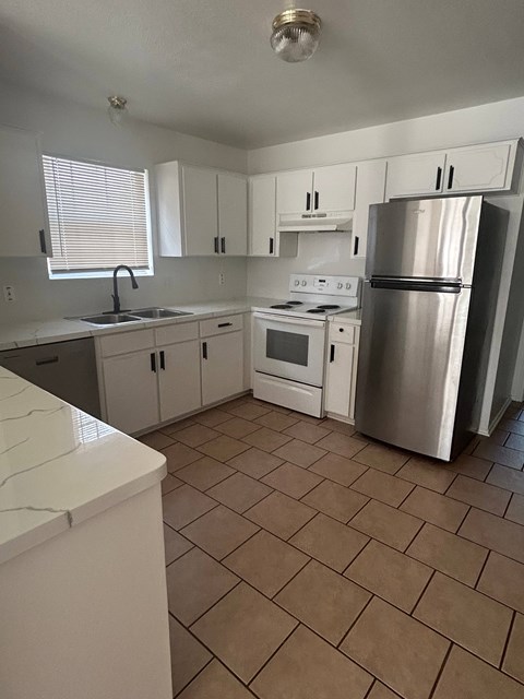 A kitchen with white cabinets and a stainless steel refrigerator.