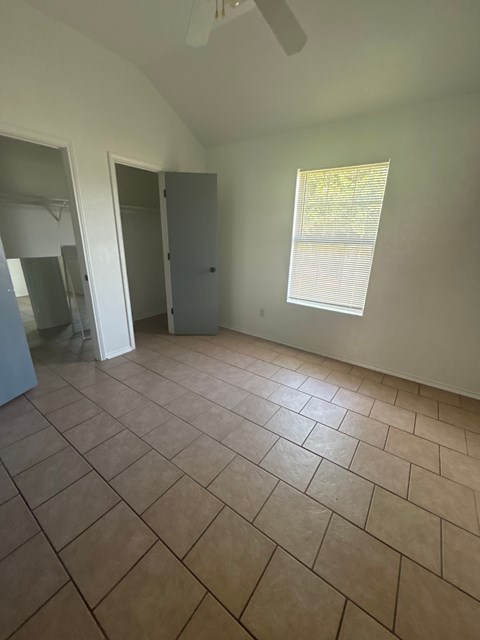 A room with a tile floor and a window with blinds.