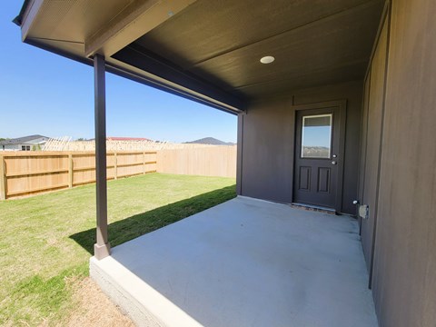 A patio with a door and a fence in the background.