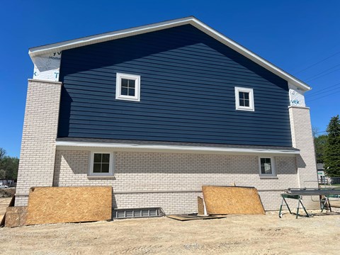 A house under construction with a blue roof and white brick walls.