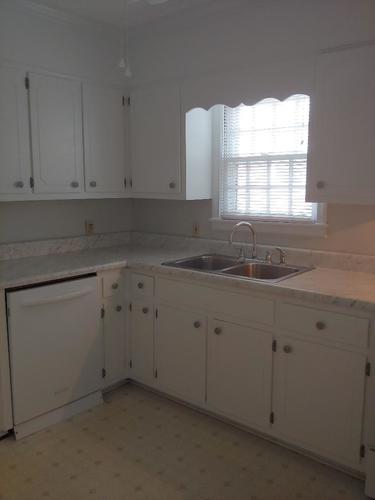 A kitchen with white cabinets and a sink.