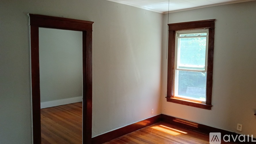 A room with a window and wooden floors is available for rent.