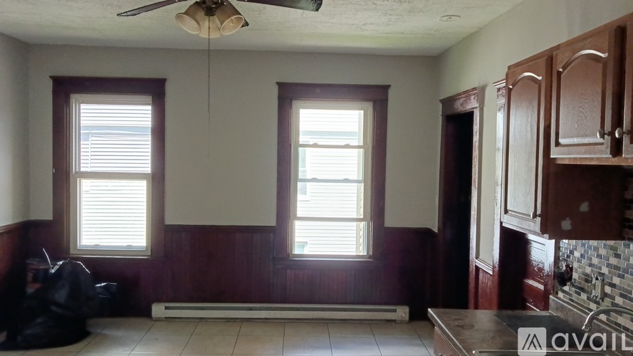 A room with a ceiling fan and two windows.