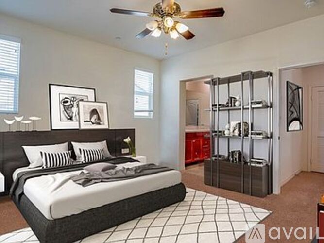 A bedroom with a black bed and a ceiling fan.