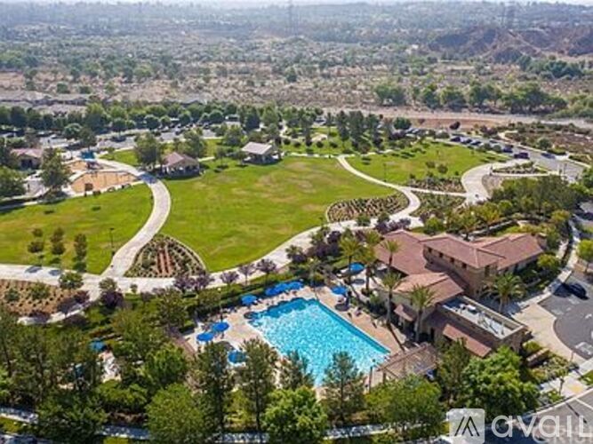 A bird's eye view of a residential area with a swimming pool and a winding road.