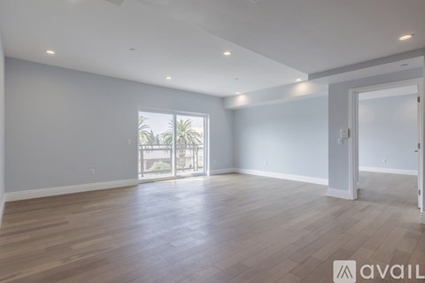 A spacious room with wooden flooring and a large window.