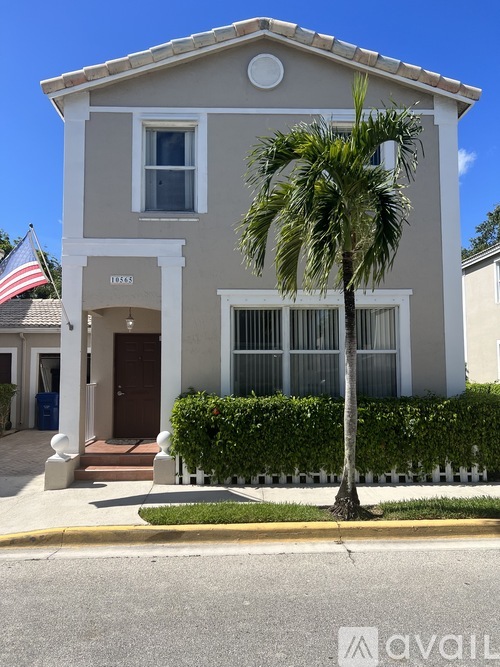 A two-story house with a palm tree in front.