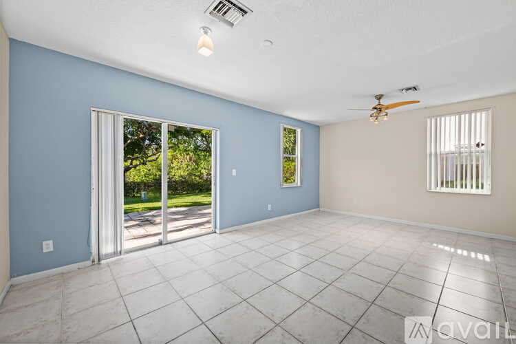 A spacious room with a ceiling fan and sliding glass doors.