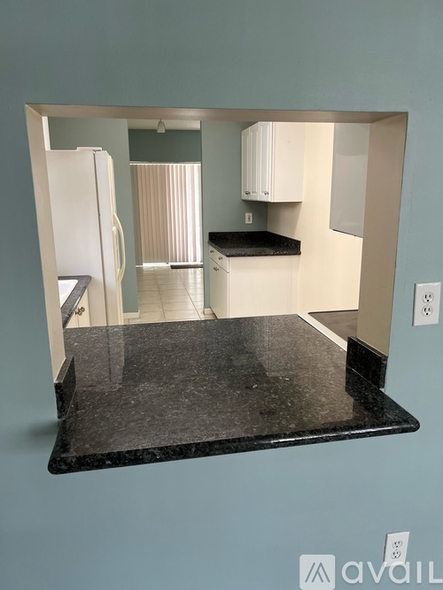 A kitchen with a black granite countertop and white cabinets.