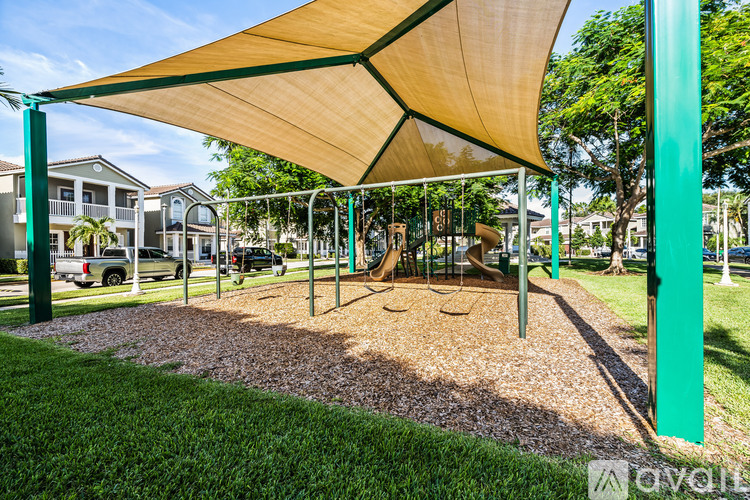 A playground with a swing set and a shade structure.