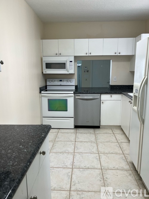 A kitchen with white cabinets and a black countertop.