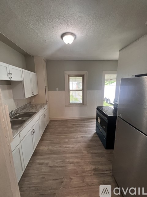 A kitchen with a refrigerator, sink, and cabinets.