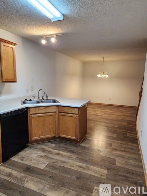 A kitchen with wooden cabinets and a black dishwasher.