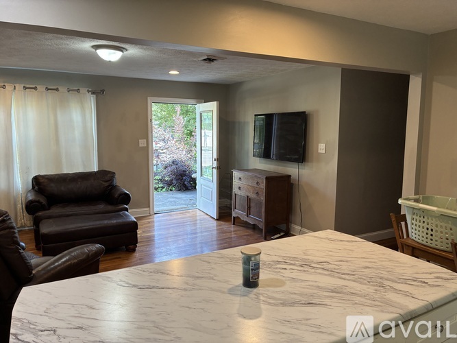 A living room with a marble table and a television on the wall.