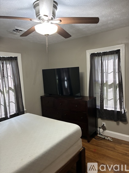 A bedroom with a bed, a television, and a ceiling fan.