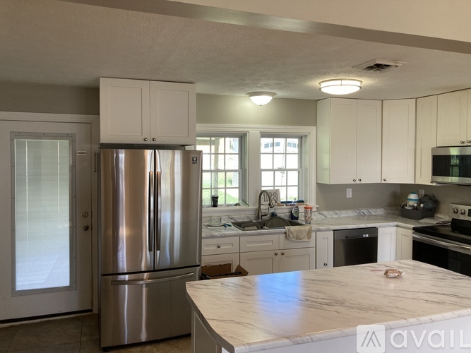 A kitchen with a stainless steel refrigerator and white cabinets.
