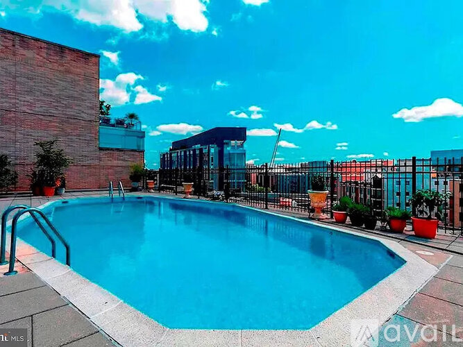 A pool surrounded by a black fence and a red brick wall.