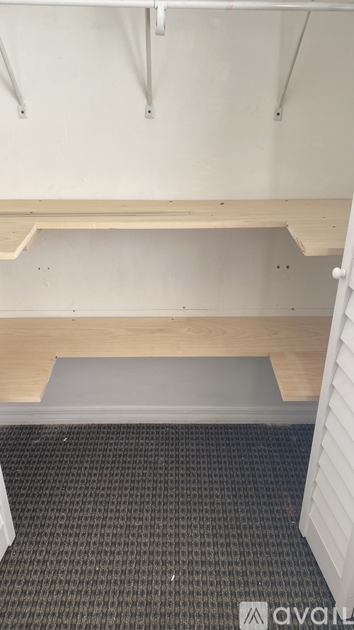 A room with a wooden bench and a grey carpet.