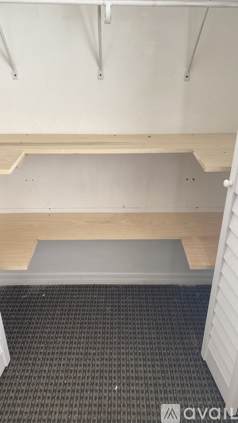 A room with a wooden bench and a grey carpet.