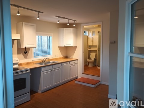 A kitchen with white cabinets and a wooden floor.