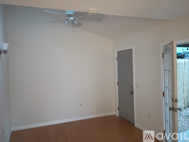 A room with a ceiling fan and a door leading to a backyard.