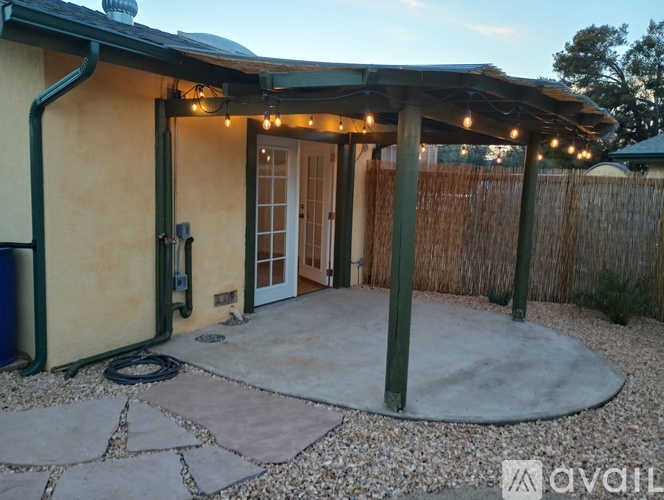 A patio area with a stone walkway and a pergola with string lights.