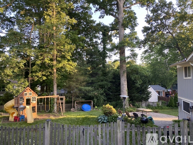 A playground with a yellow slide and a blue ball is surrounded by a wooden fence.