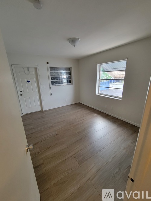 A room with wooden flooring and a window with blinds.