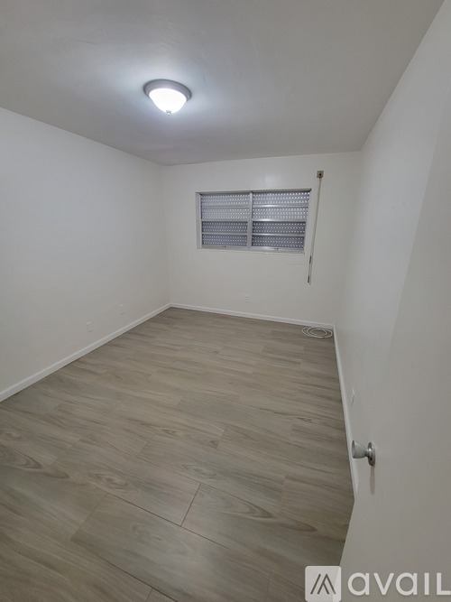 A room with wooden flooring and a window with blinds.