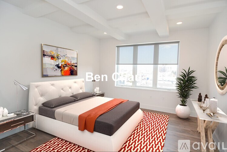A bedroom with a white bed and a red and black striped blanket.