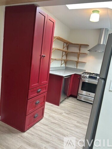 A red kitchen cabinet with a stove and oven in the background.