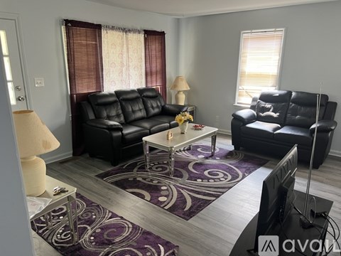 A living room with a black leather couch and a white coffee table.