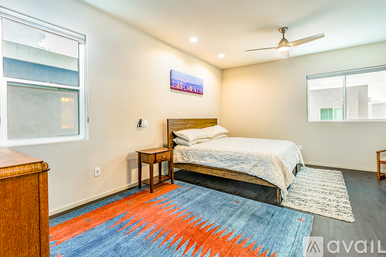 A bedroom with a bed, a ceiling fan, and a window.