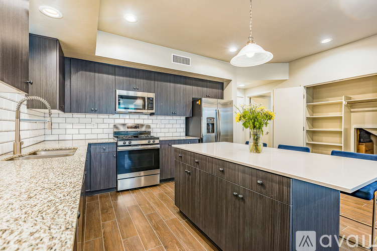 A modern kitchen with dark wood cabinets and a white countertop.