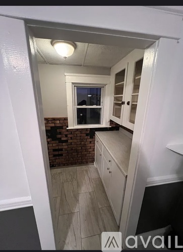 A kitchen with white cabinets and a brick wall.