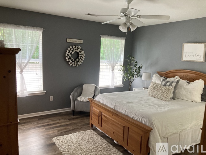 A bedroom with a bed, chair, and a wreath on the wall.
