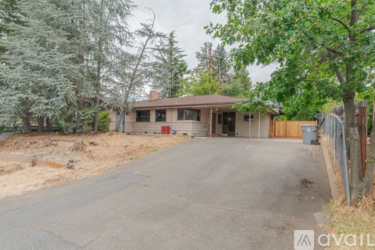 A house with a driveway in front of it surrounded by trees.