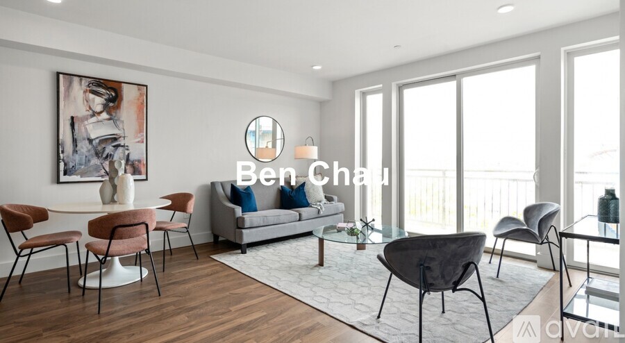 A modern living room with a sofa, chairs, and a painting on the wall.