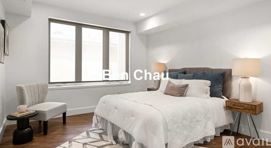 A bedroom with a large bed, a chair, and a nightstand with a lamp.
