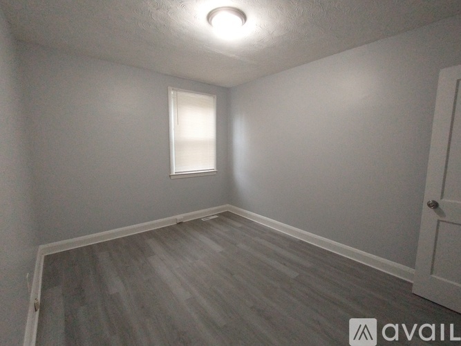 A room with a window and wooden flooring.