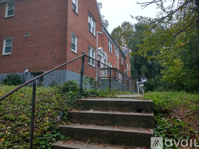 A red brick building with a metal fence and stairs leading up to it.