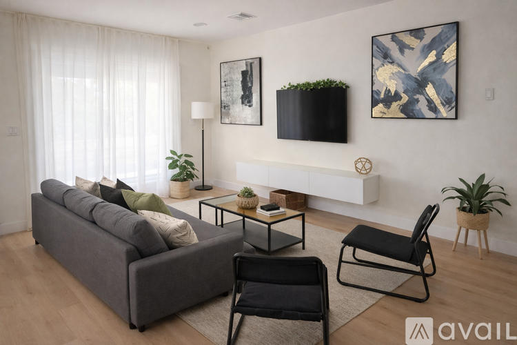 A living room with a grey couch, a black chair, a small table, and a painting on the wall.
