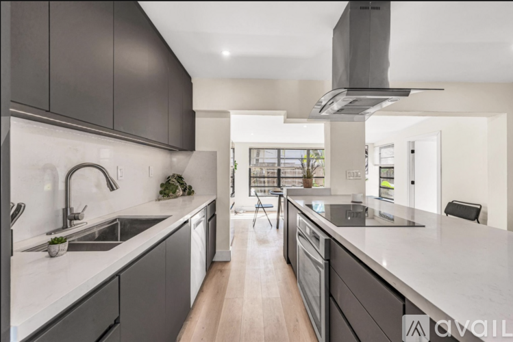 A modern kitchen with dark grey cabinets and a white countertop.