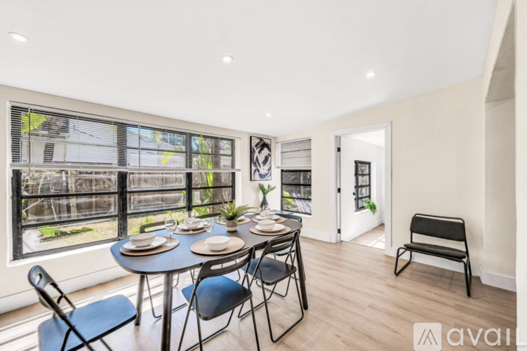 A dining room with a table set for four and a view of a garden outside.