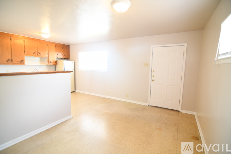A kitchen area with white walls and wooden cabinets.