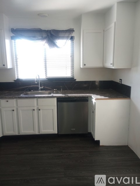 A kitchen with white cabinets and a black countertop.